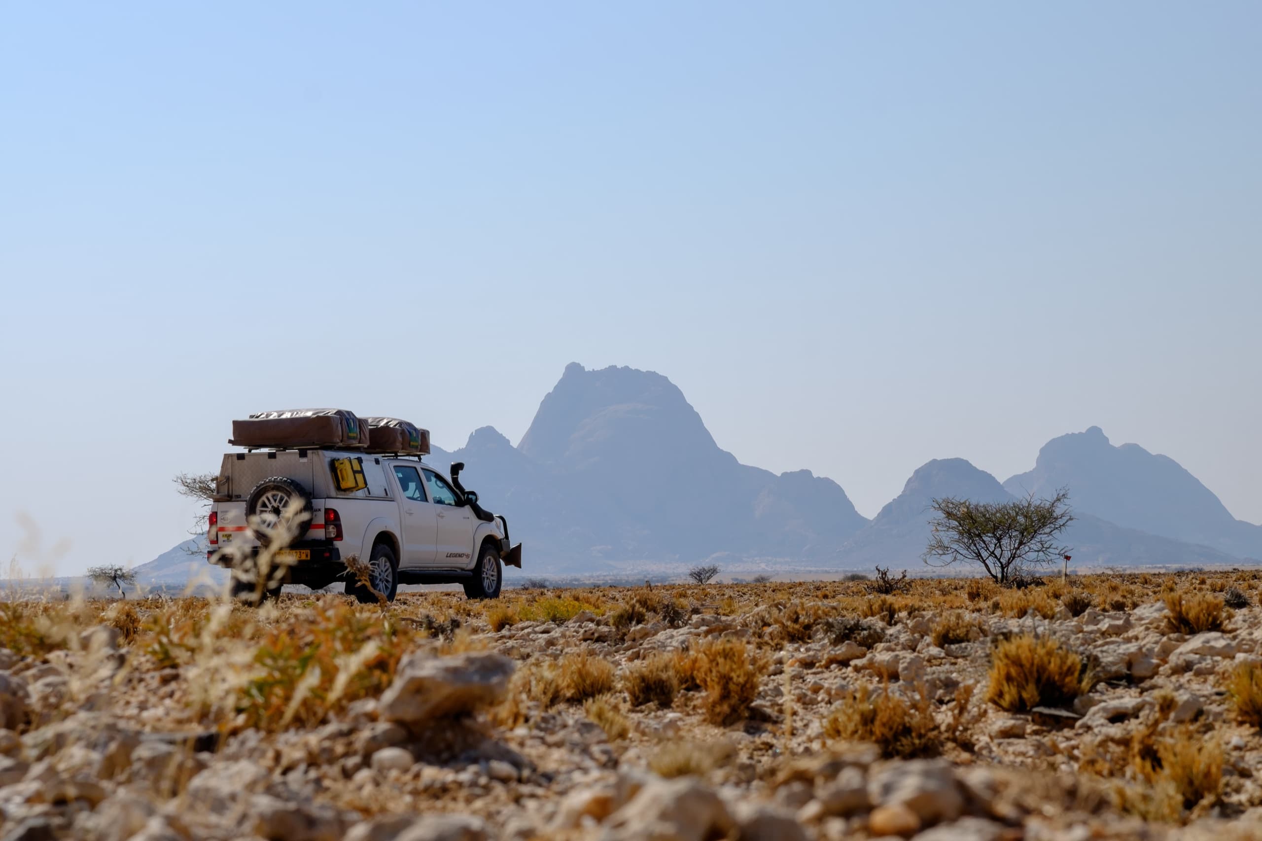 Overland expedition vehicle with roof tent crossing remote desert terrain